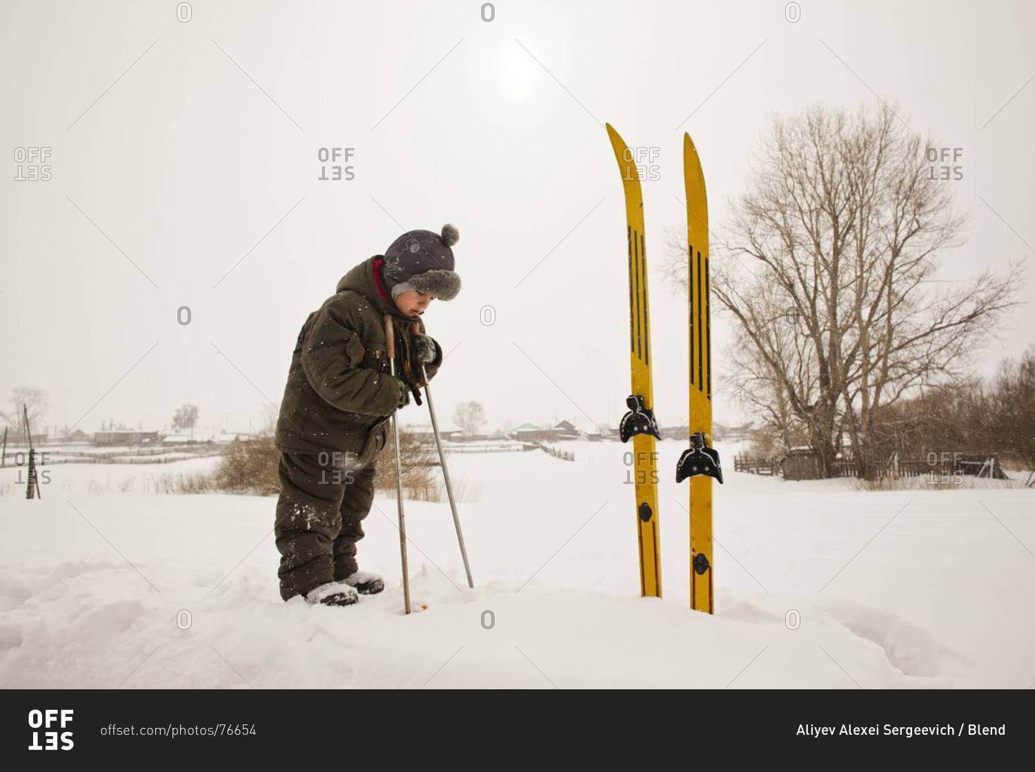 Asian boy playing with skis in snow