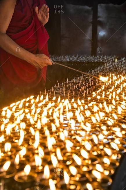 Monk lighting prayer candles at the Mahabodhi Temple in Bodh Gaya, India