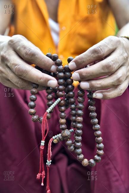 Detail of a Buddhist monk holding prayer beads. Mahabodhi Temple, Bodh Gaya, India