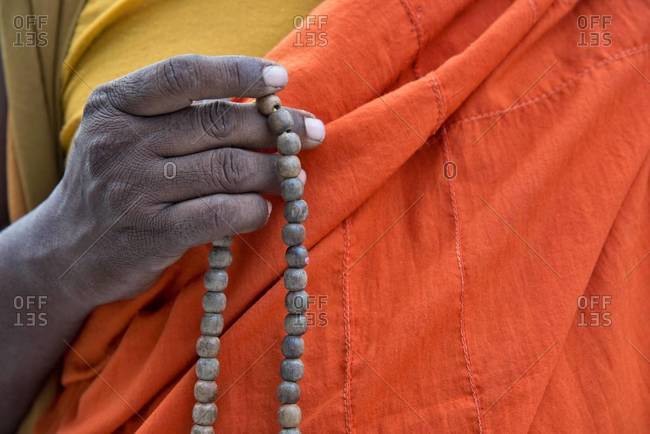 Detail of a Buddhist monk holding prayer beads. Mahabodhi Temple, Bodh Gaya, India