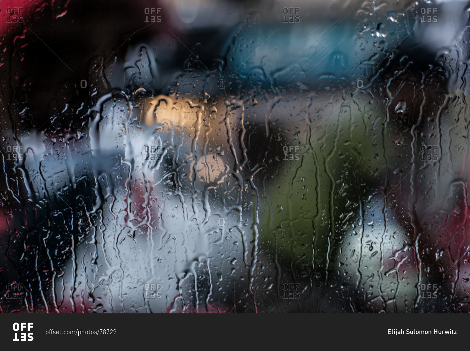 Rain soaked window silhouettes a tuk-tuk driver in New Delhi
