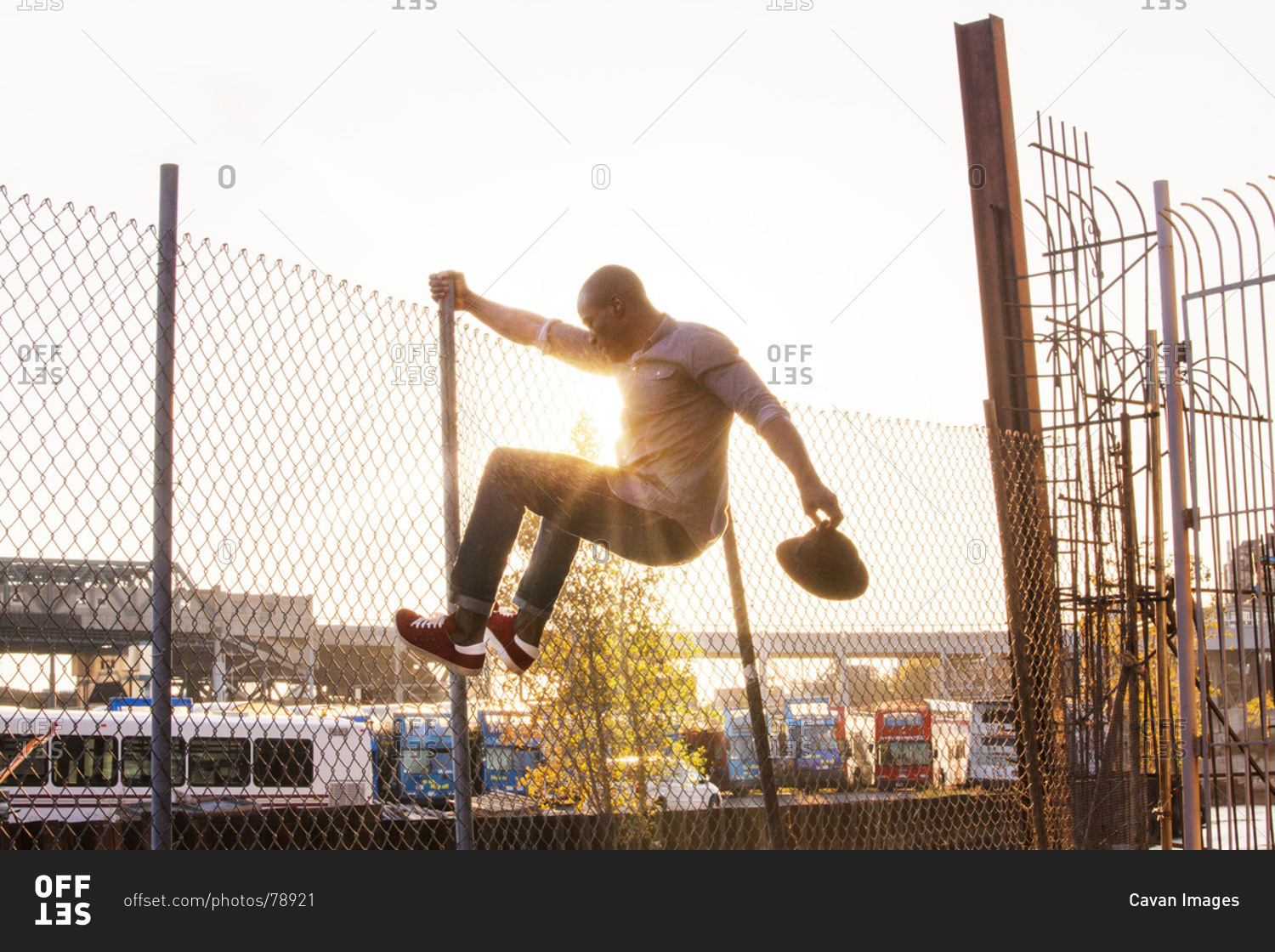 Silhouette of African American man tries to jump over wire fence