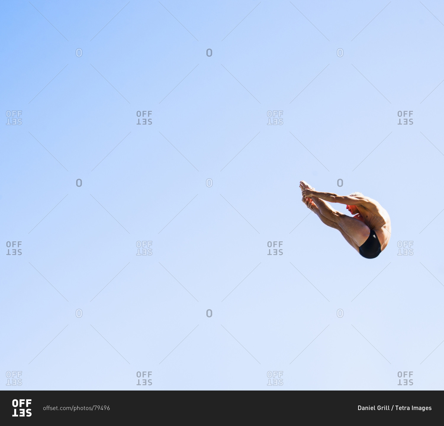 Athletic swimmer mid-air against blue sky