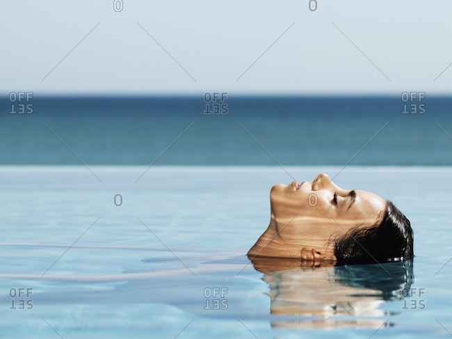 Woman dipping head back in pool