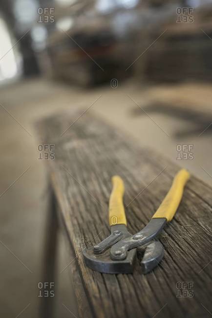 A heap of recycled reclaimed timber planks of wood. Environmentally responsible reclamation in a timber yard. A pair of pliers on a plank of wood.
