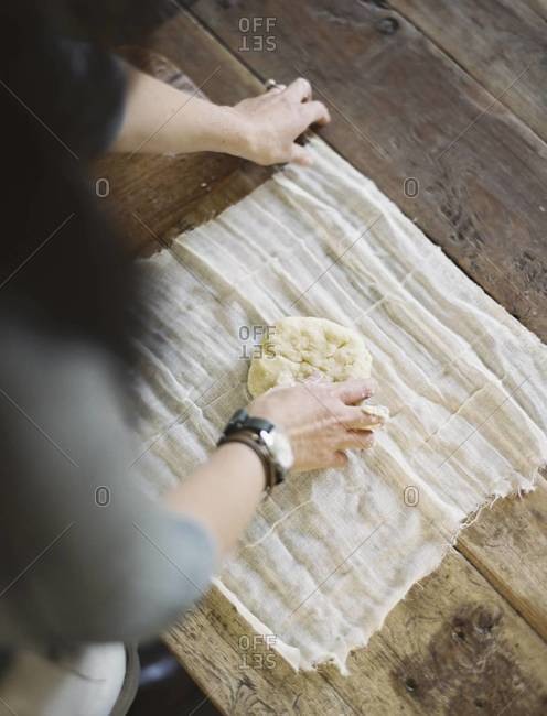 A view from above of a woman wrapping fresh pastry in a muslin cloth to keep it fresh.