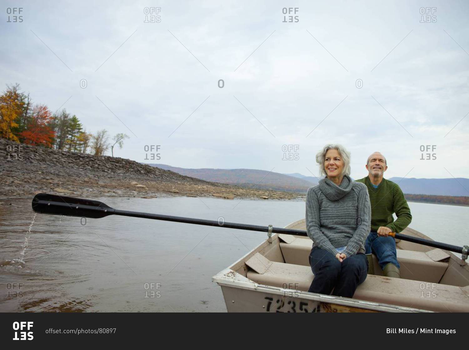 A couple, man and woman sitting in a rowing boat on the water on an autumn day