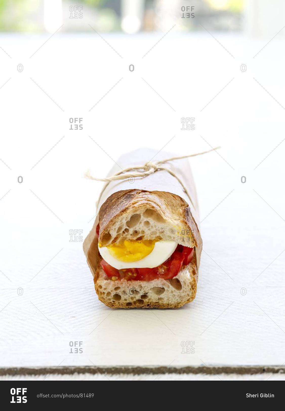 Boiled egg and tomato sandwich in French baguette, wrapped in wax paper