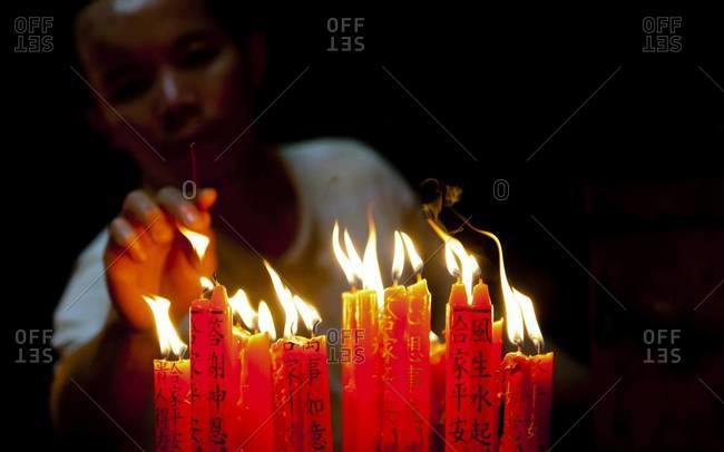 HO CHI MINH CITY, VIETNAM - January 25, 2012: A man lights candles in a temple as an act of ancestor worship