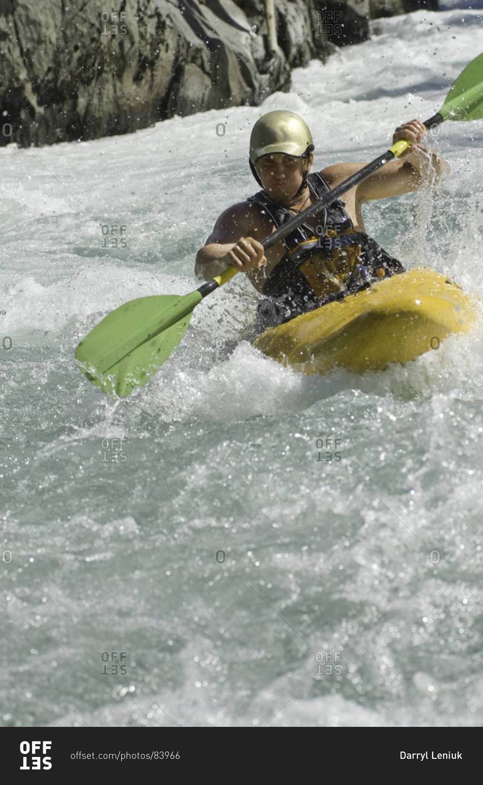 Male kayaking rough waters in white water kayak