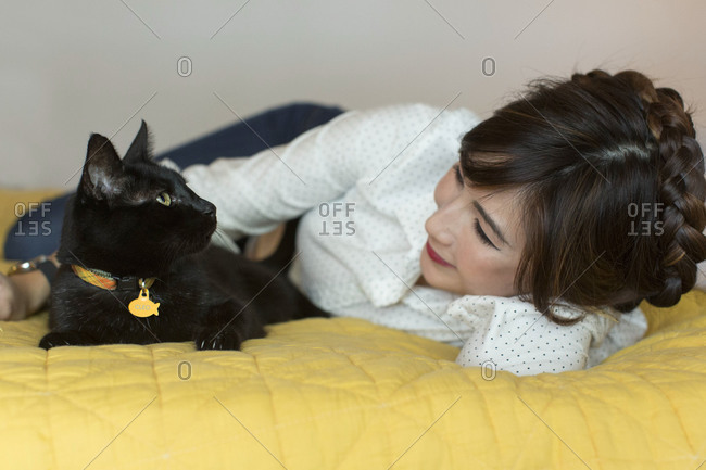Black cat and woman looking at each other on bed