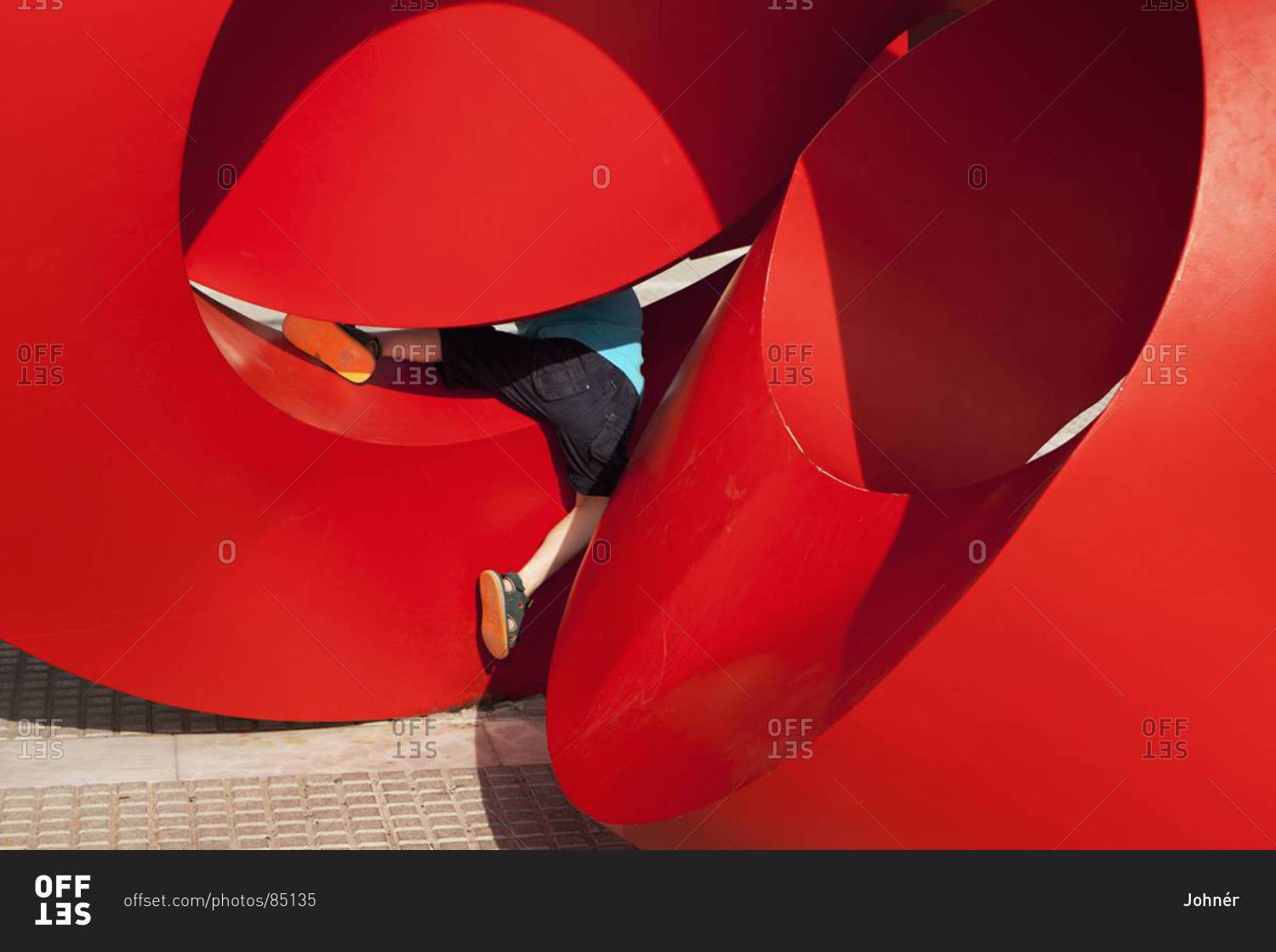 Child playing on red modern sculpture, Spain