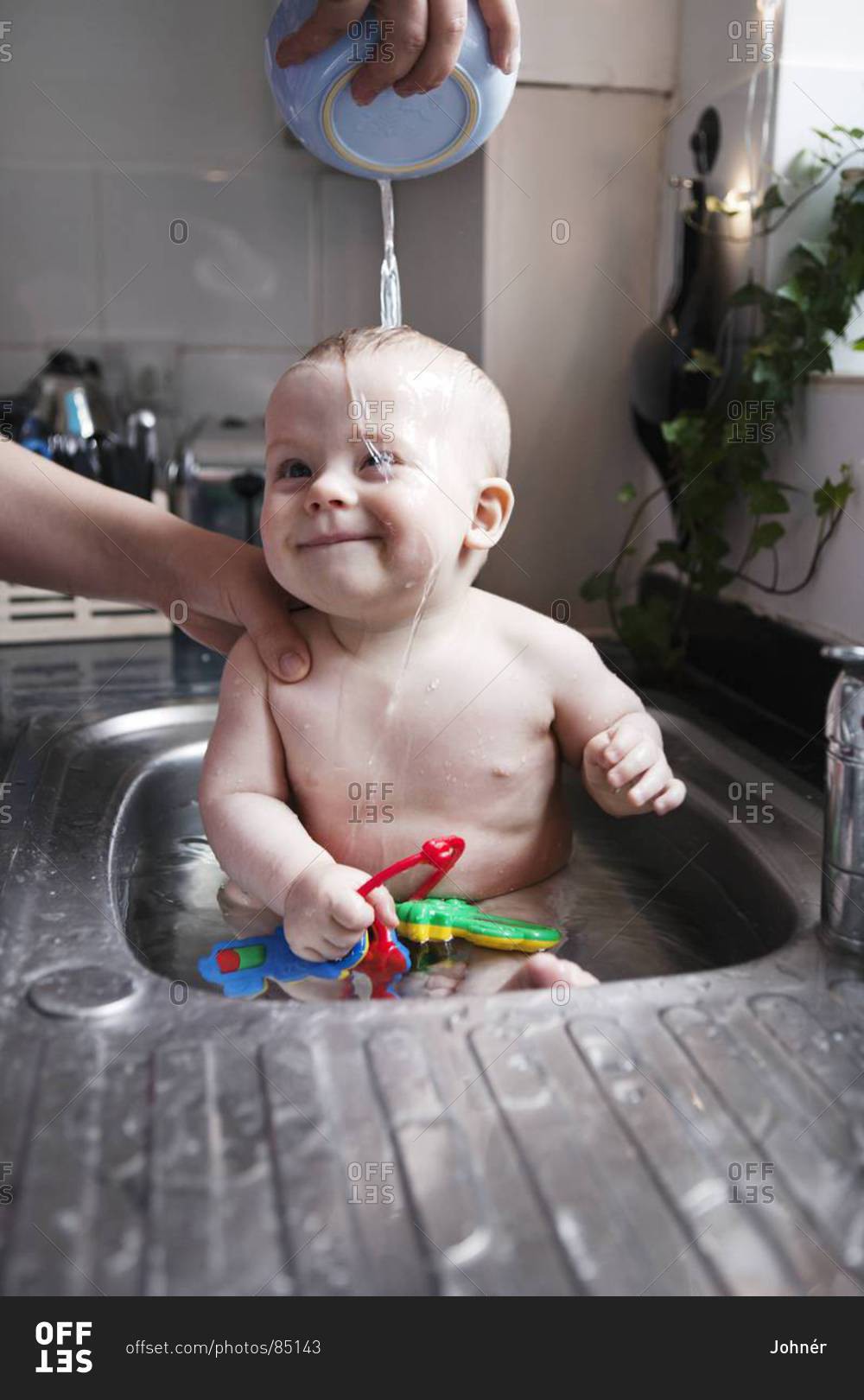 Baby having bath in sink, London, United Kingdom stock photo OFFSET