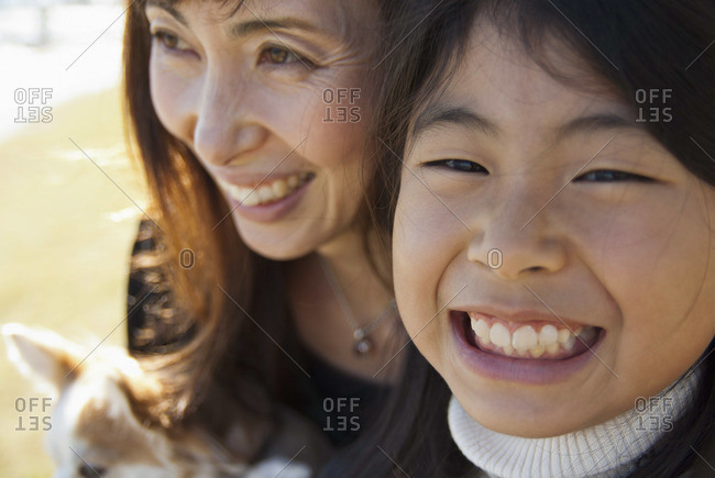A grinning mother and daughter with dog, close-up