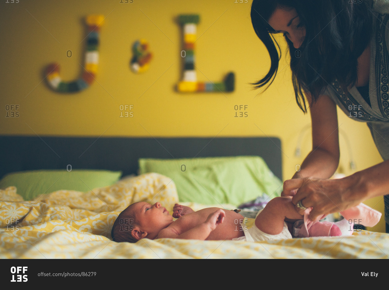 Mother dressing newborn on bed stock photo OFFSET