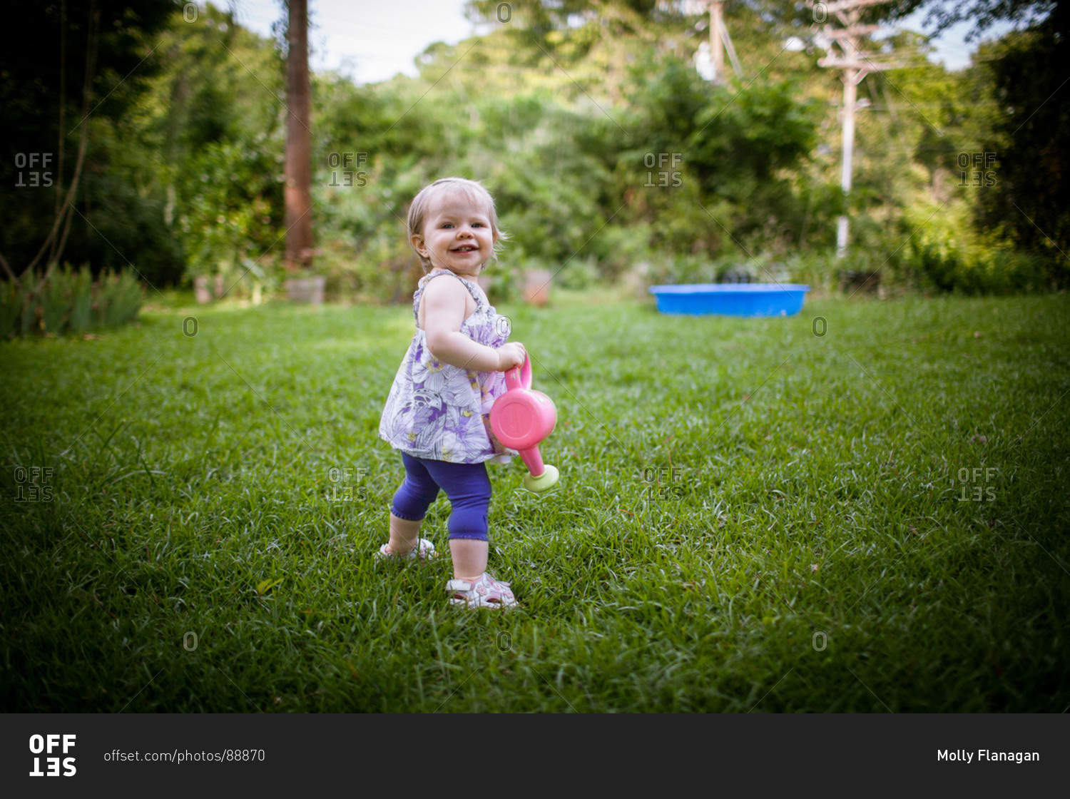 Little girl walking in garden with watering pot