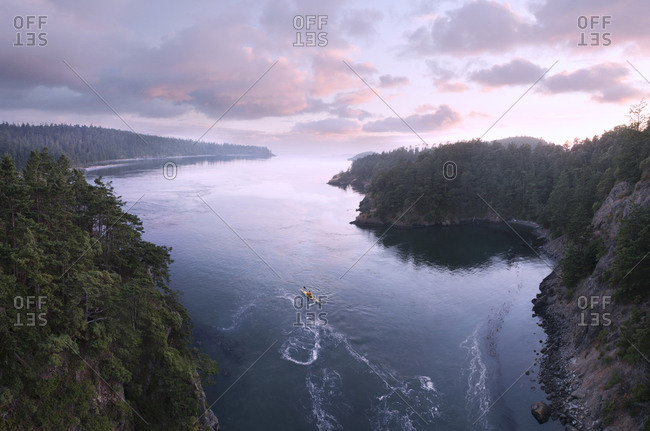 A sea kayaker paddles the currents at Deception Pass at Twilight.