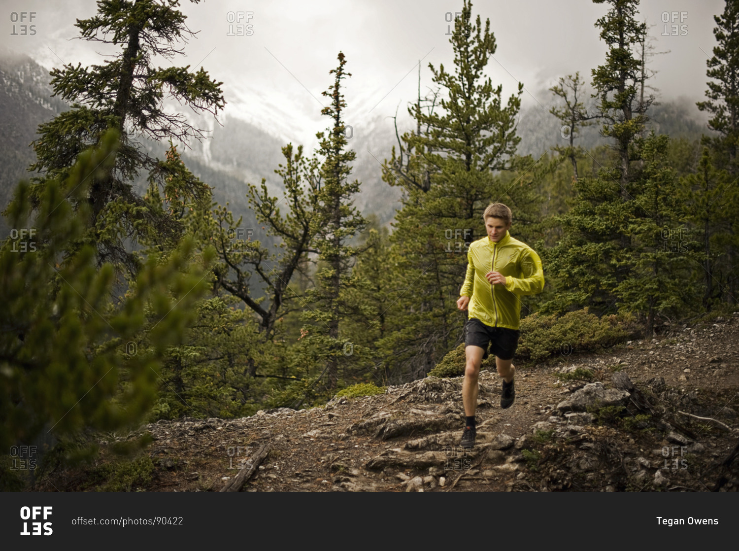 Athletic young man runs on a mountain trail