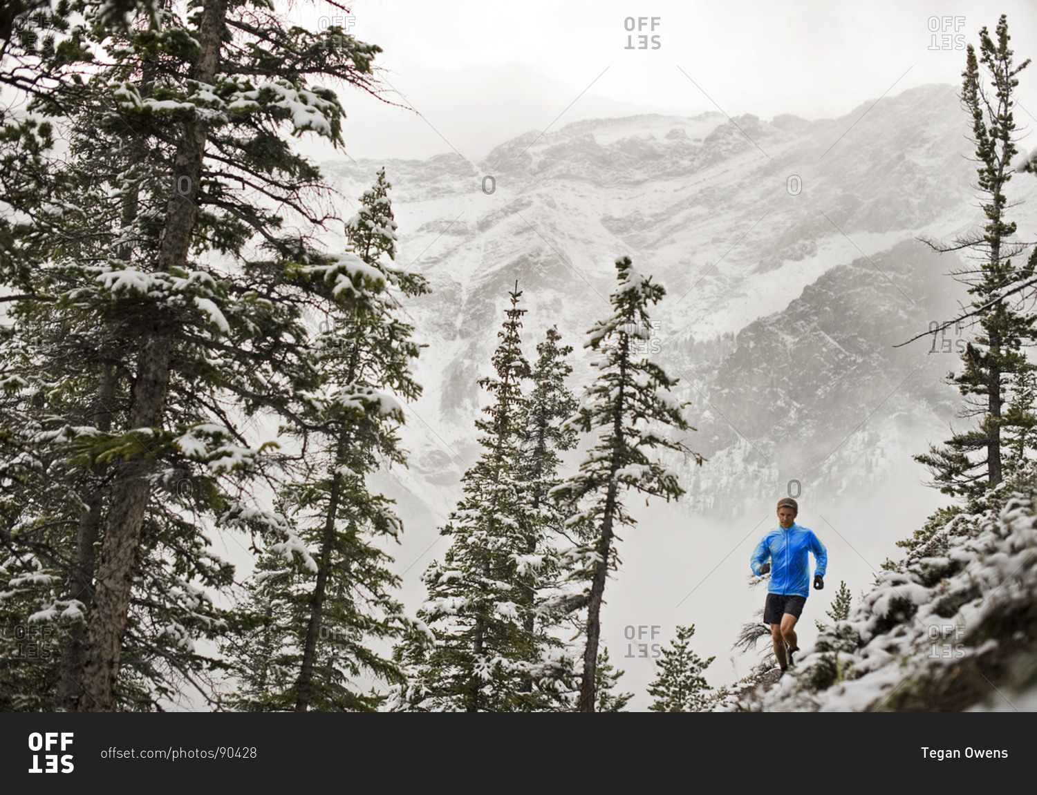 Athletic young man running along mountain's edge