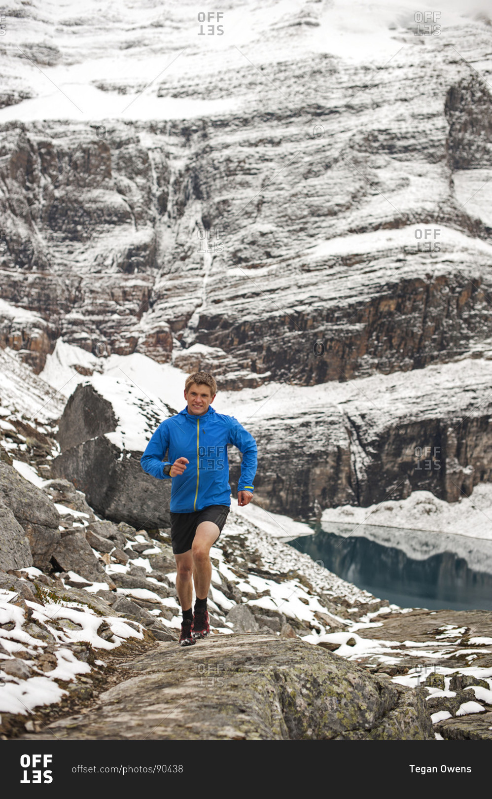 Athletic young man running happily along winter mountain trail