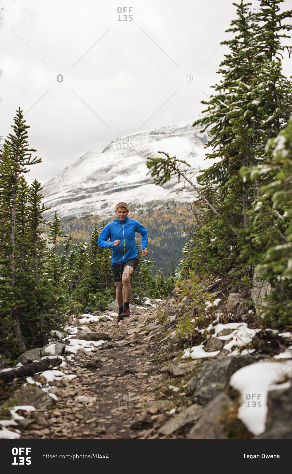 Athletic young man runs on a snowy mountain trail