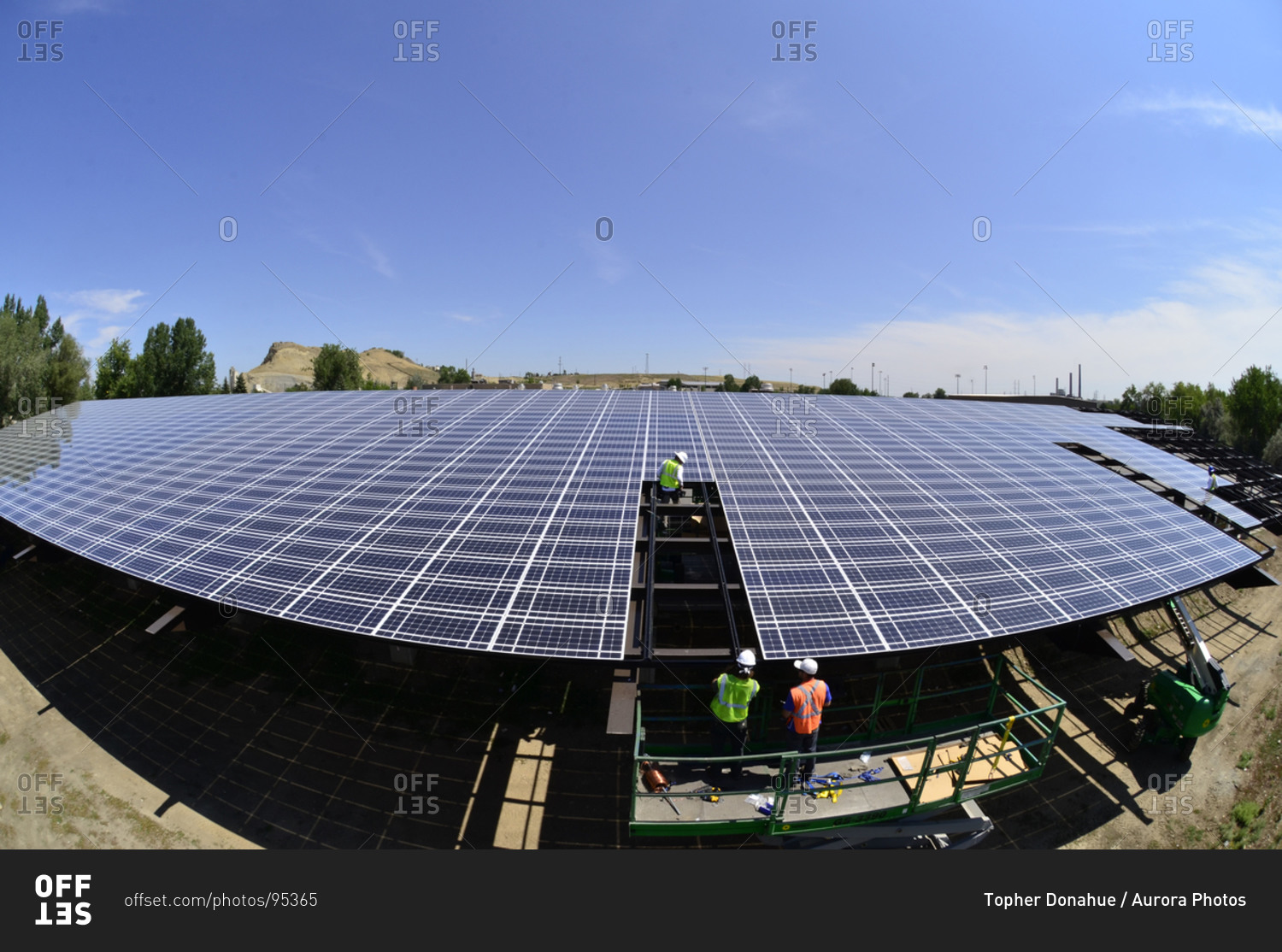 A team installs solar panels over a fueling station for garbage trucks.