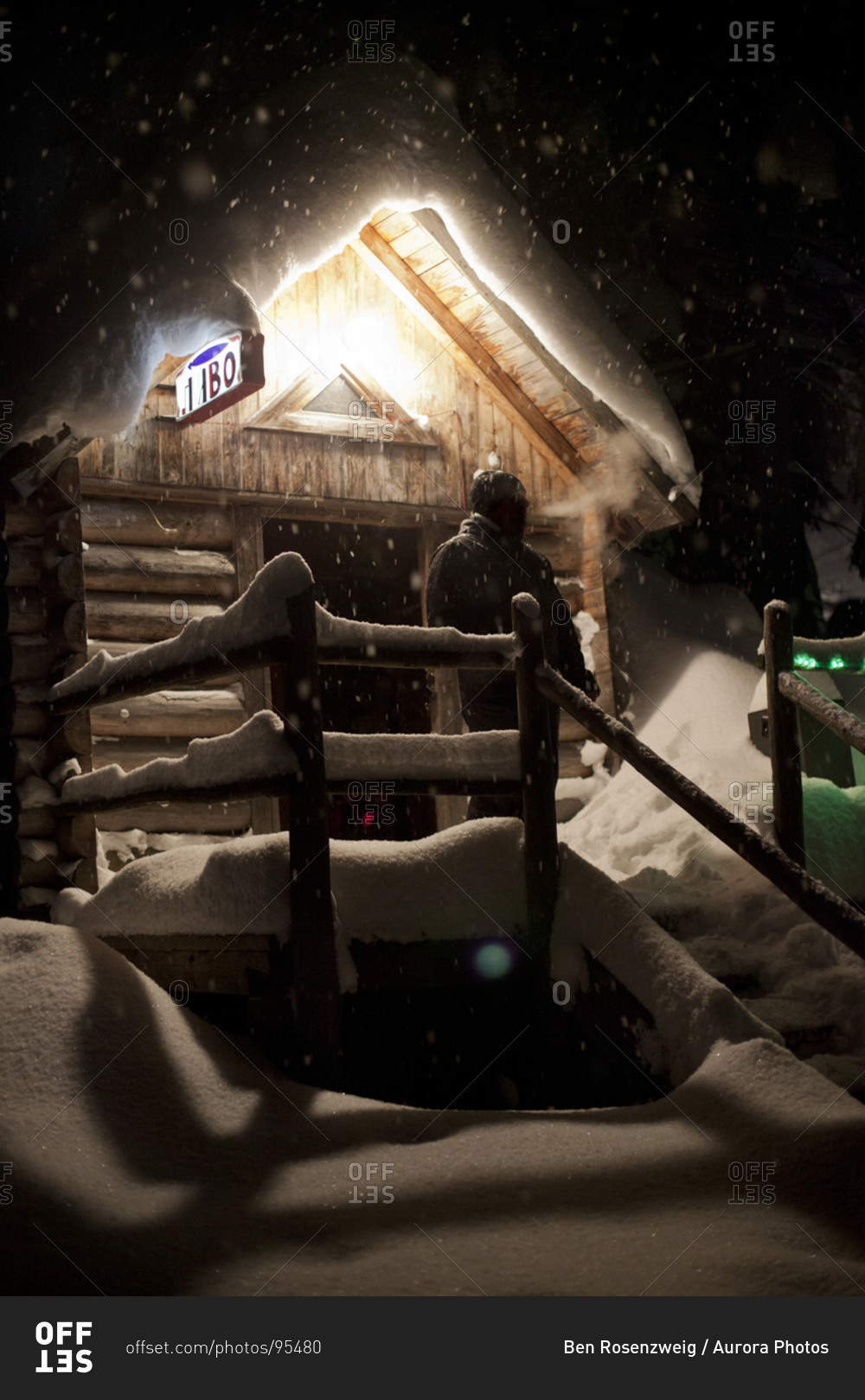 A man smokes a cigarette outside of a snow covered rustic bar with a sign that reads beer during a snowstorm in Dragobrat, Ukraine.