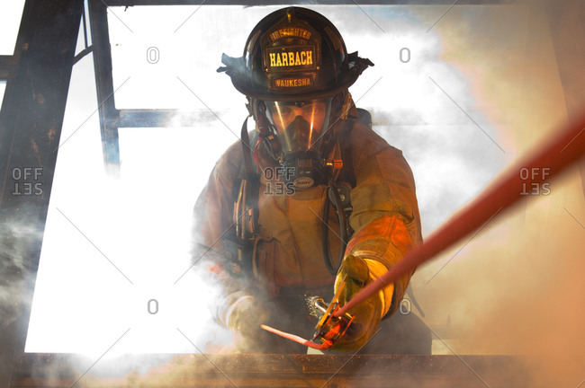 A firefighter practices fast escape drills while surrounded by simulated explosions, smoke and fire.