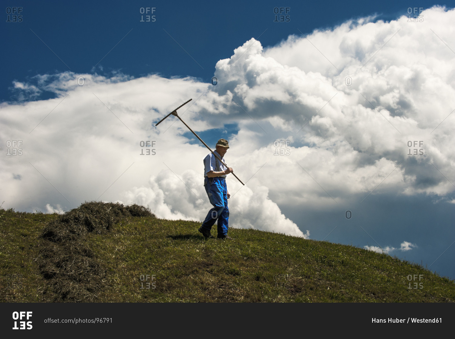 Austria, Radstadt, farmer on field, upcoming thunderstorm in the background