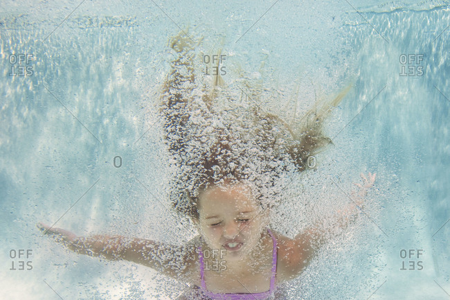 Girl jumping into the pool stock photo - OFFSET