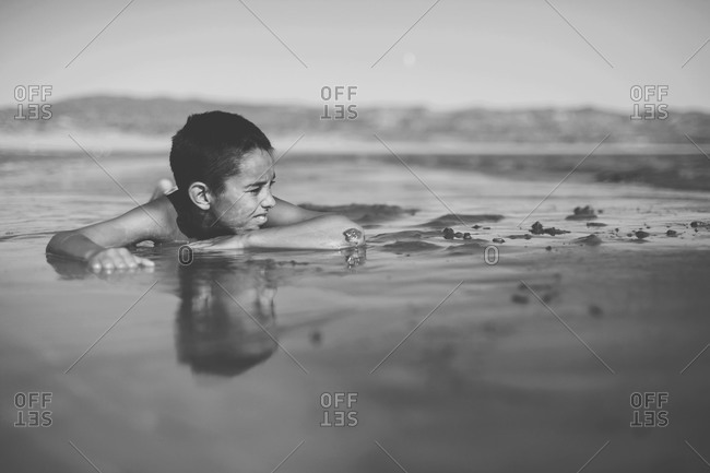 Boy lying in the shallow water