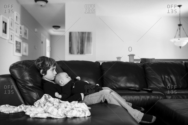 Side view of brother and little sister watching TV in living room