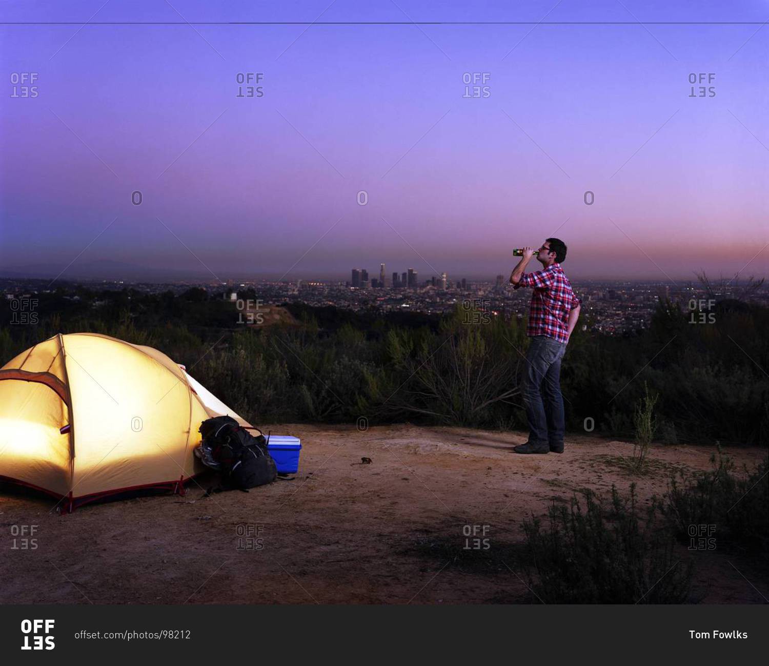 A man drinks beer near a tent
