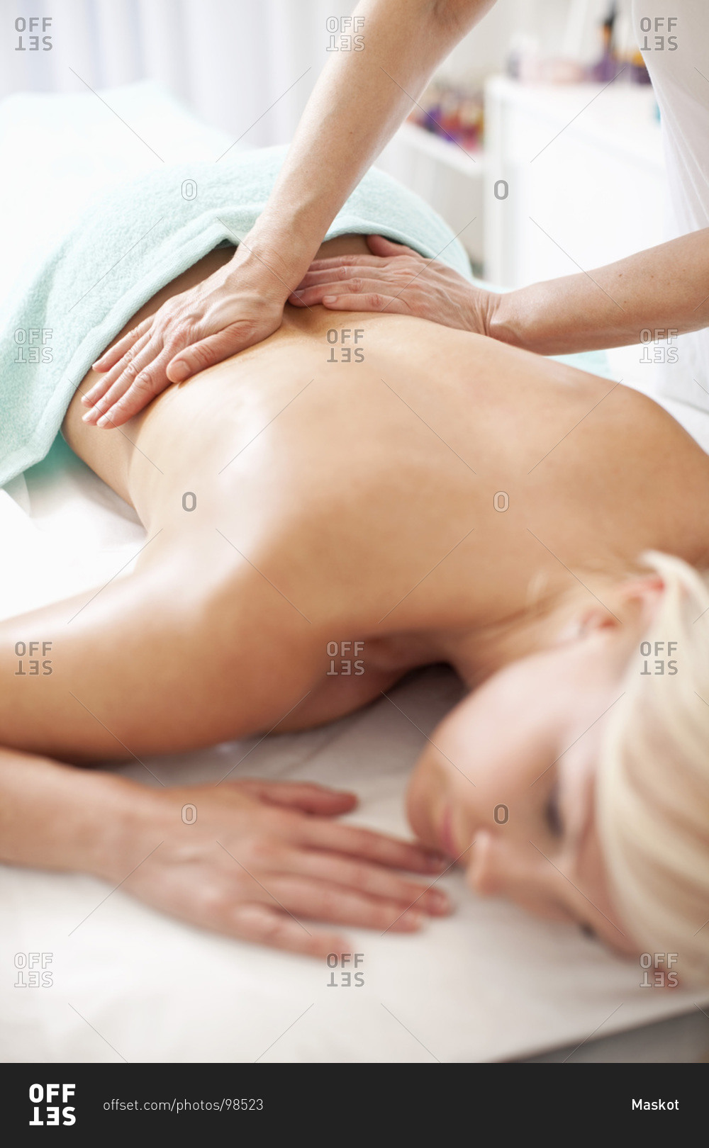 Mid adult woman receiving back massage from masseur at health spa