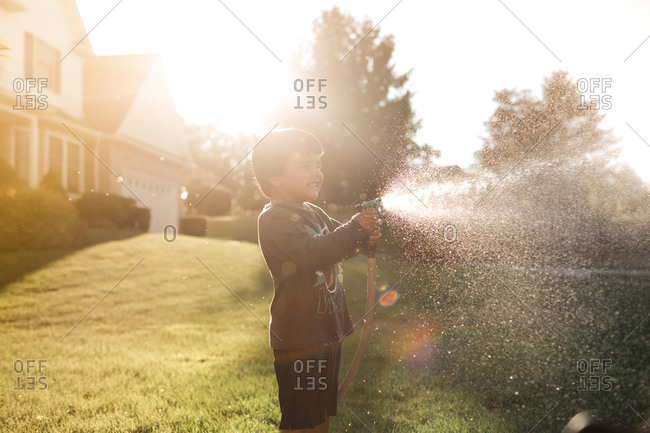 Boy spraying garden hose - Offset