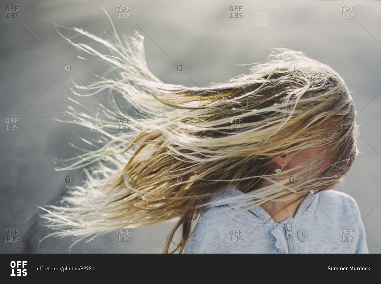A blonde girl's hair blowing in the wind, obscuring her face