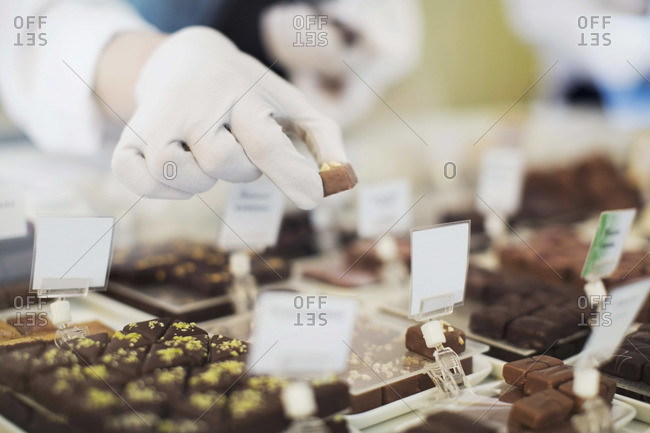 Cropped Image Of Worker Holding Sweet Food At Display Cabinet At
