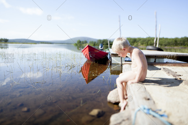 Naked boy sitting at lake stock photo pic