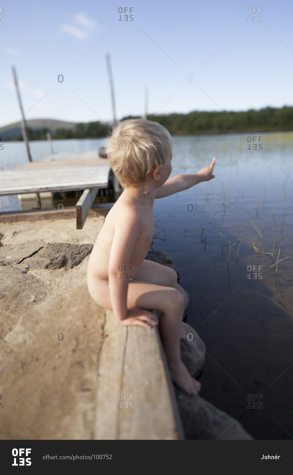 Naked boy sitting at lake