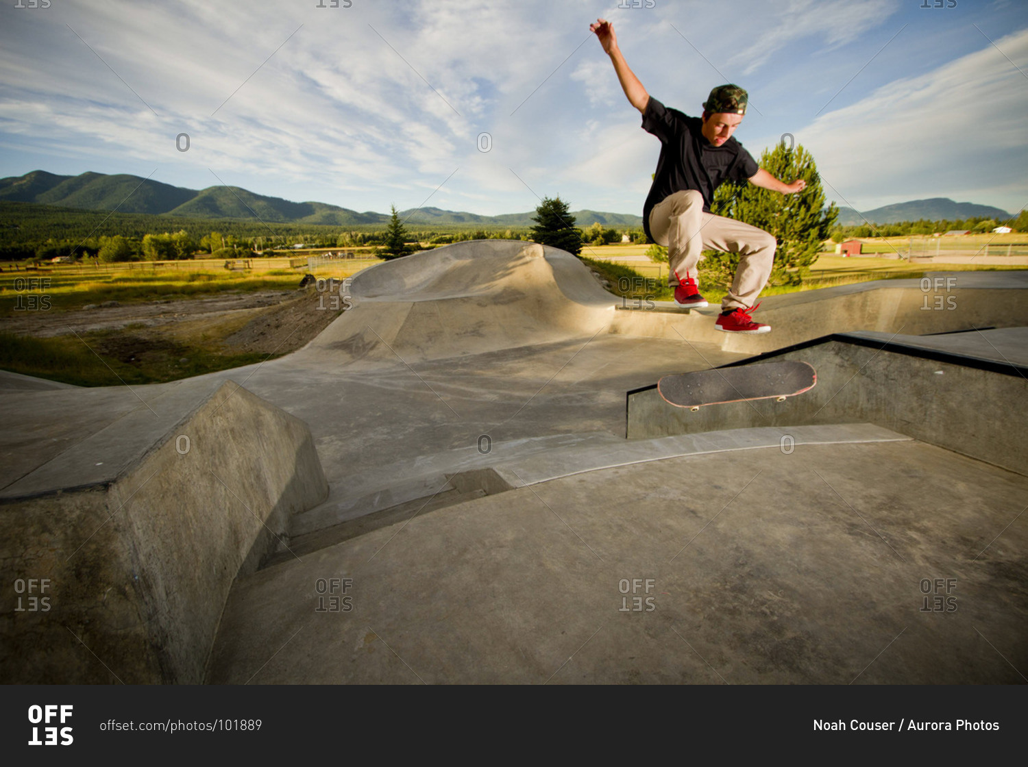 A skater flips his skateboard up a ramp at the skatepark in Whitefish, Montana on a cloudy summer day.