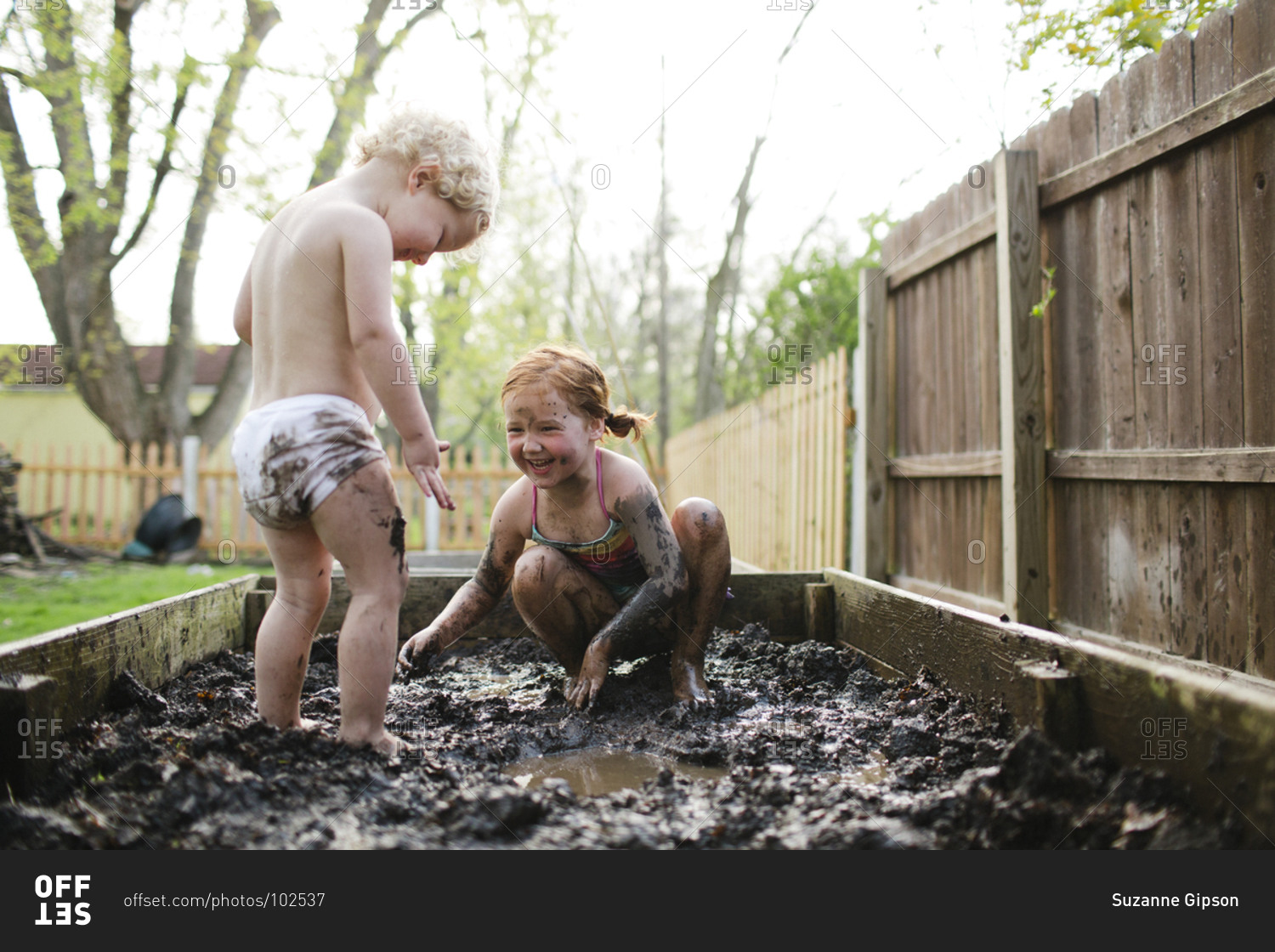 Children covered in mud on the beach stock photo - OFFSET