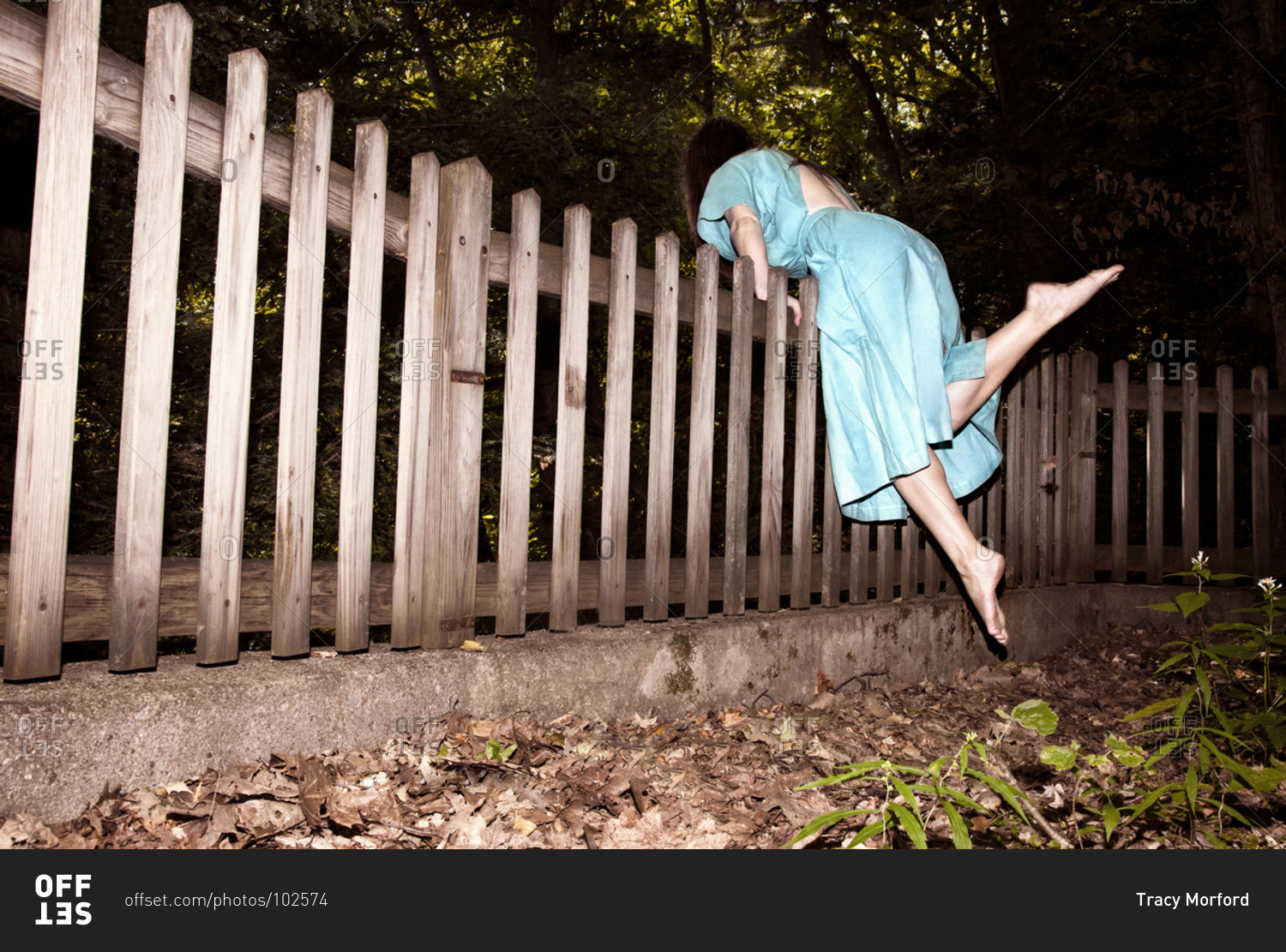 Woman climbing over a fence stock photo OFFSET