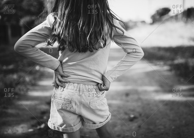 Back view of a girl standing on a dirt road