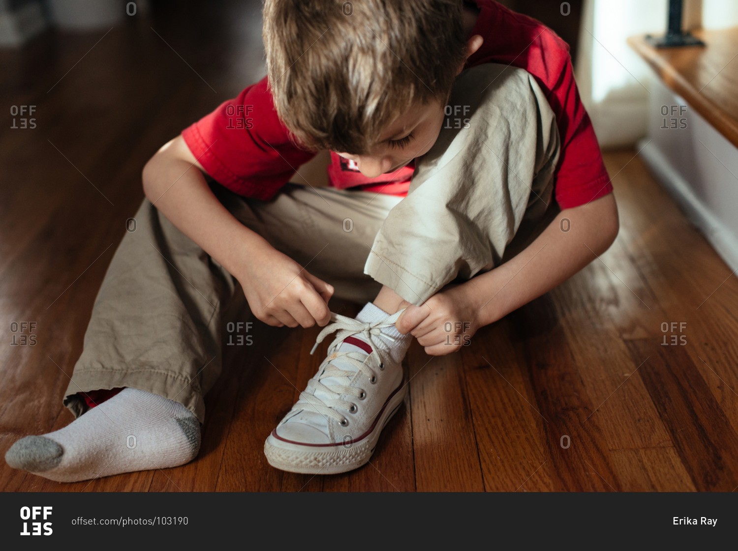 You boy tying his shoelace stock photo - OFFSET