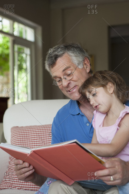 Caucasian man reading to granddaughter