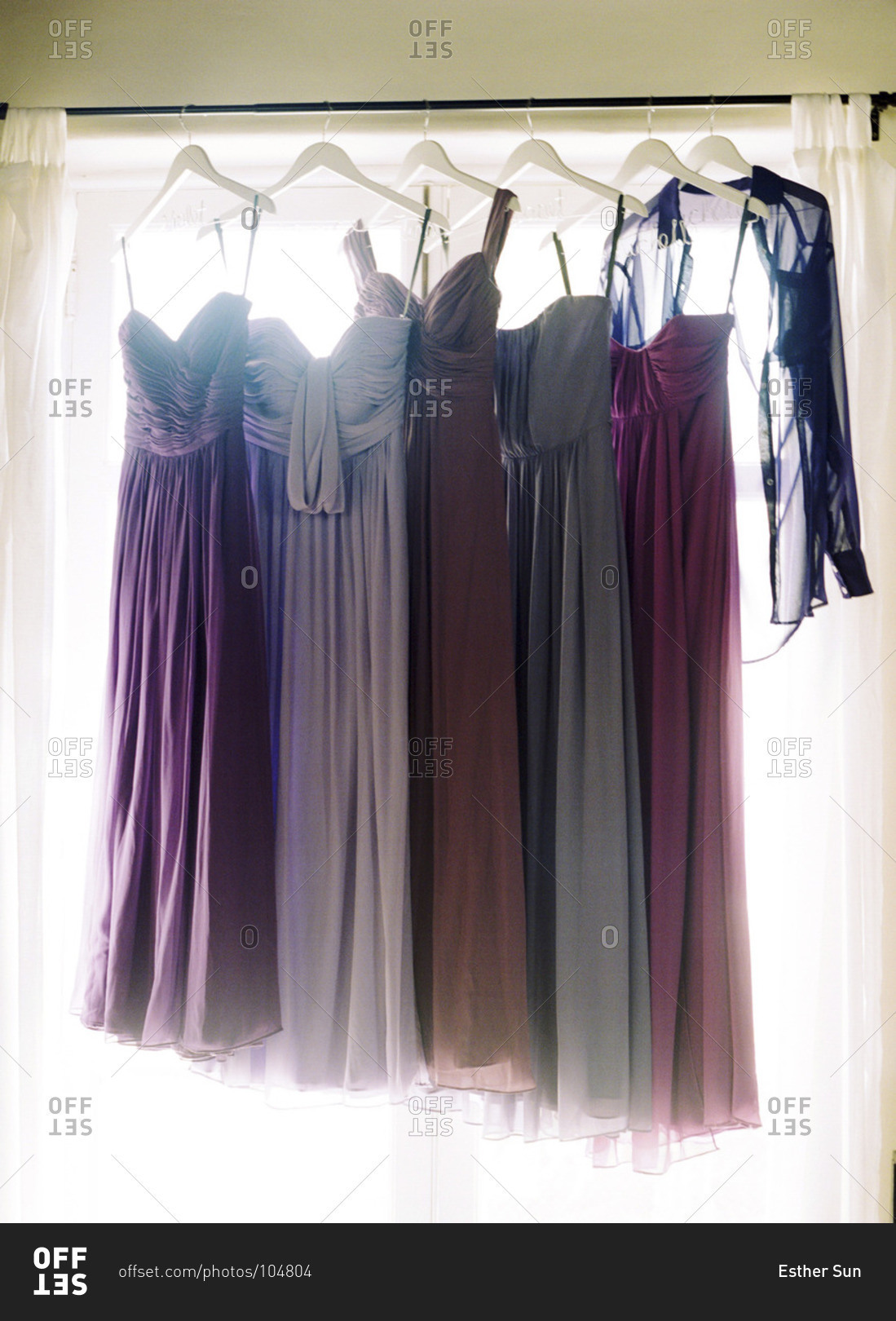 Bridesmaids' dresses hanging by a window
