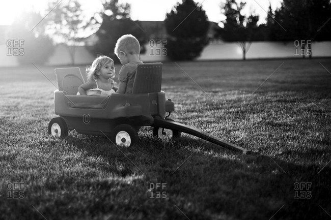 Young boy and girl sitting in a toy cart