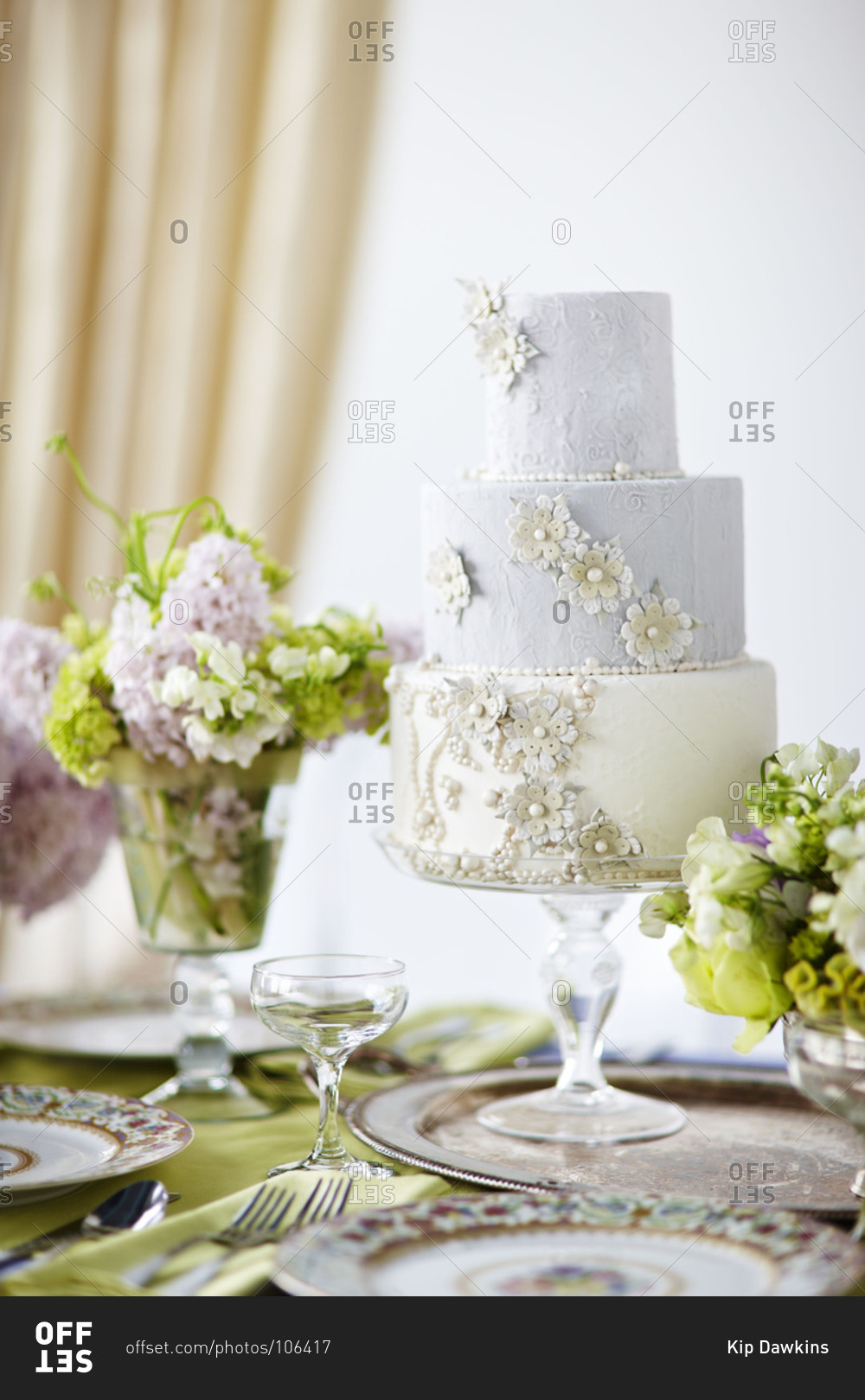 Three-tiered wedding cake with floral decoration stock photo - OFFSET