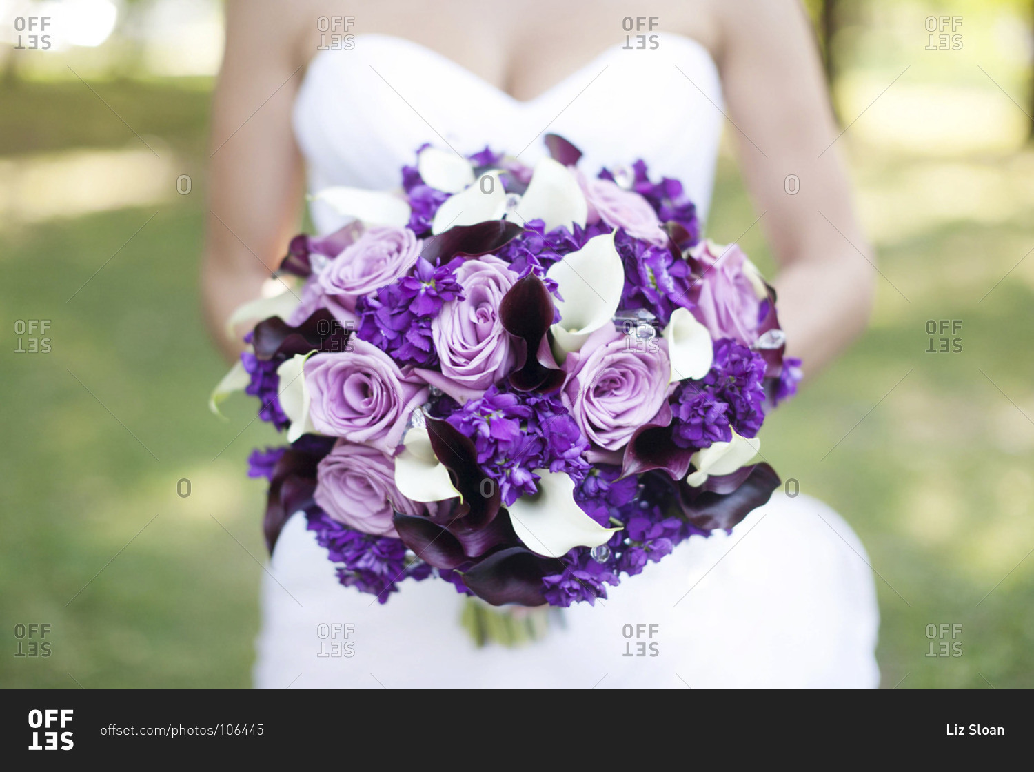 Mid section view of bride holding purple and white bridal bouquet