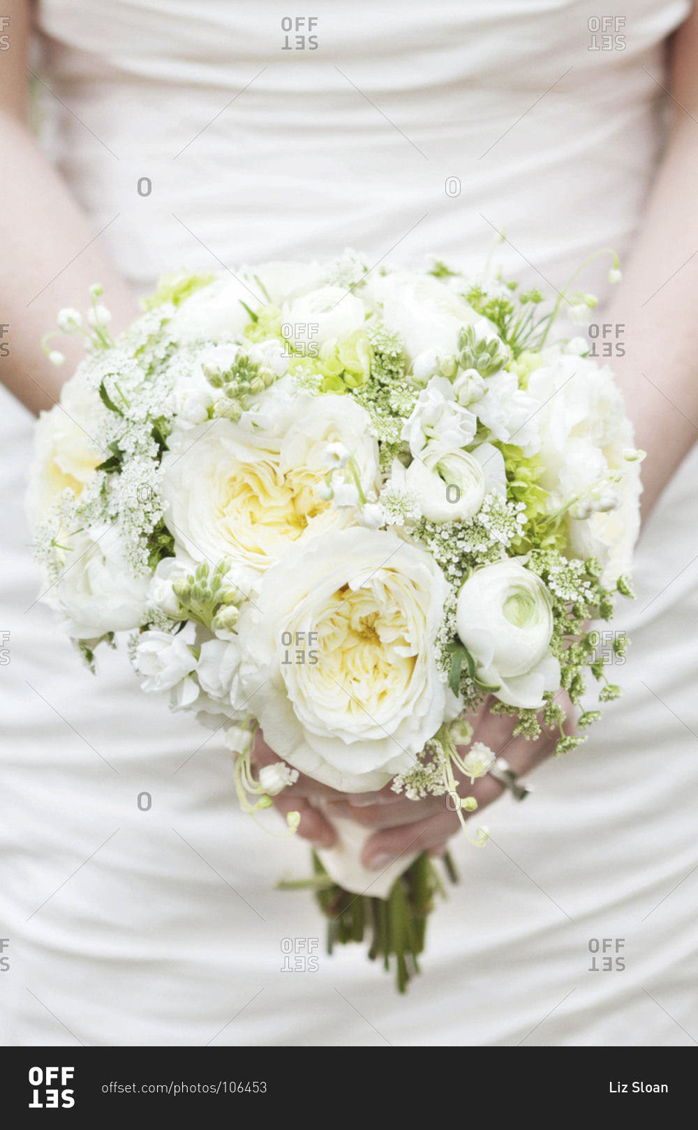 Mid section view of bride holding white peony bridal bouquet